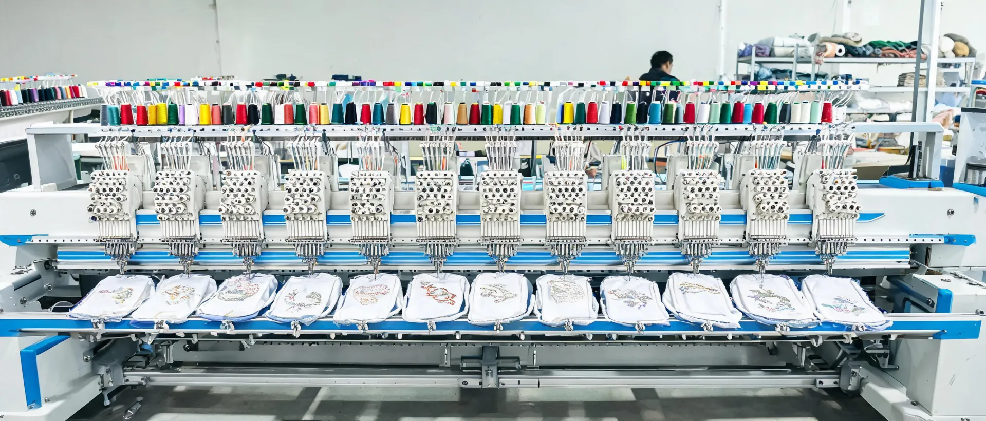 Multi-head embroidery system producing decorated apparel in a working production cell